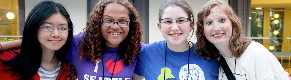 Four girls sit side by side smiling for the camera