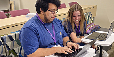 Two individuals working together on laptops.