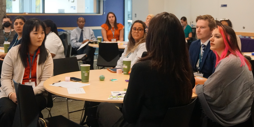 Participants sit around tables and discuss.