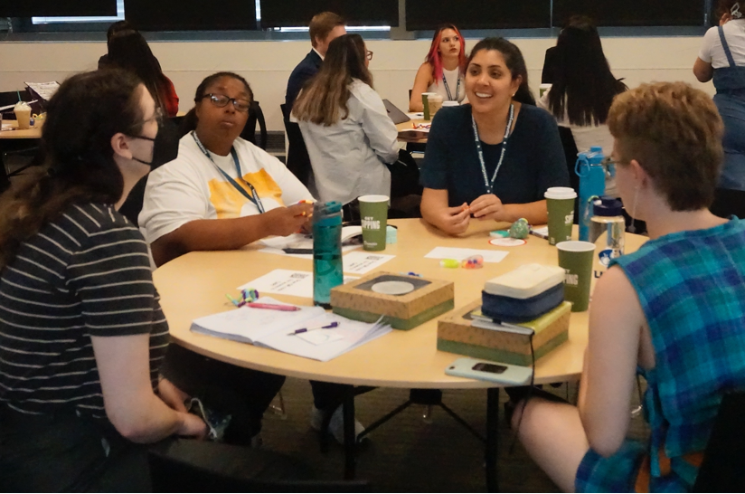 Participants laugh and share discussion around a table.