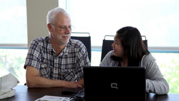 A instructor and a student working together on a laptop.