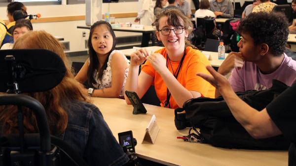 A group of students sitting around a table, engaging in a discussion.