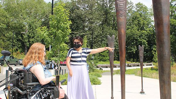 A woman in a wheelchair and another woman standing and pointing outside