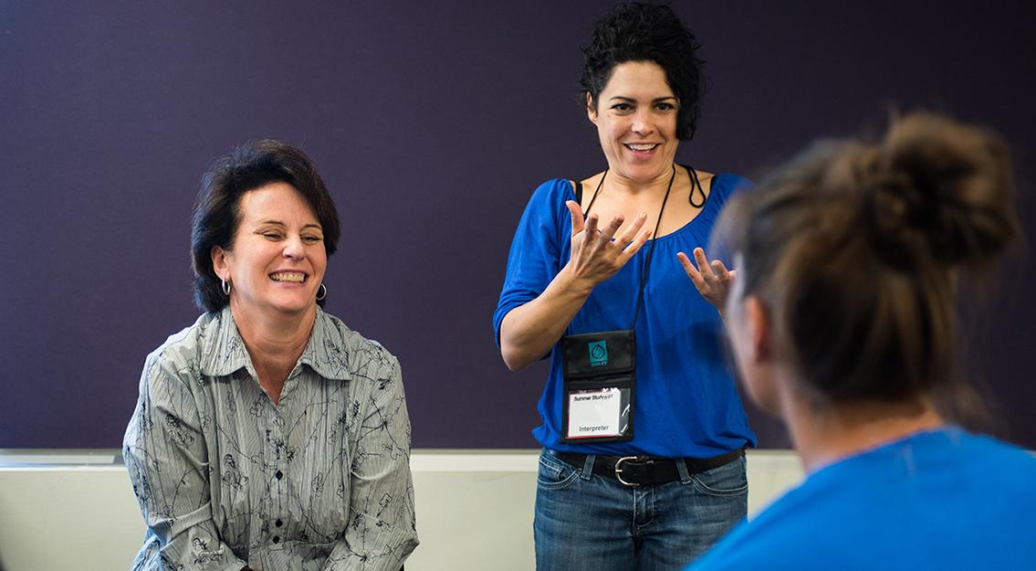 An instructor talks to a student with a sign language interpreter.