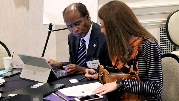 Two attendees from the AccessINCLUDES conference look over notes at a table.