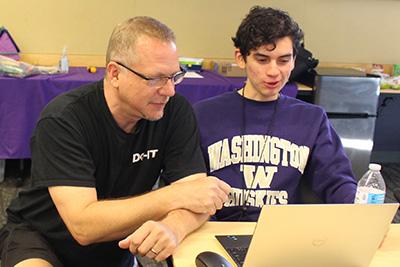 DO-IT Director Scott Bellman works with a student on a laptop